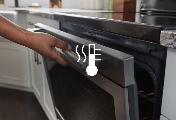 A person wiping down a Maytag® range with a sponge.