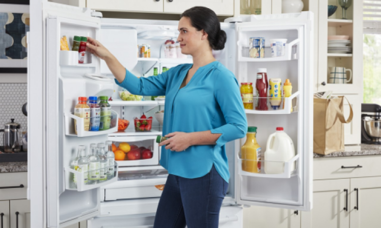 A person putting an item in the door of a Maytag® refrigerator
