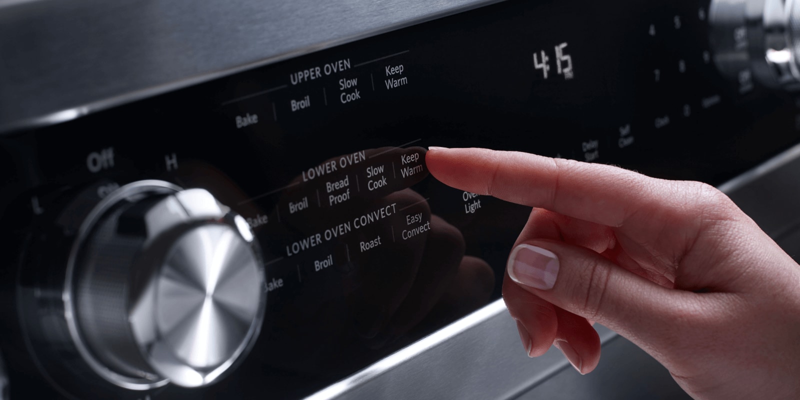 A person selects an oven setting from a range's control panel. A person selects an oven setting from a range's control panel.
