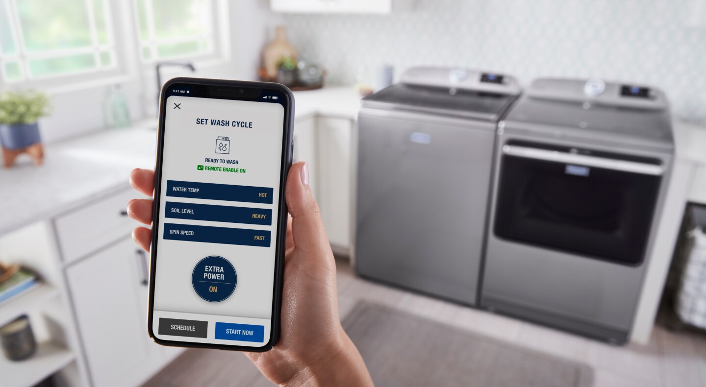 Someone using a smartphone to control a Maytag® washer and dryer Someone using a smartphone to control a Maytag® washer and dryer