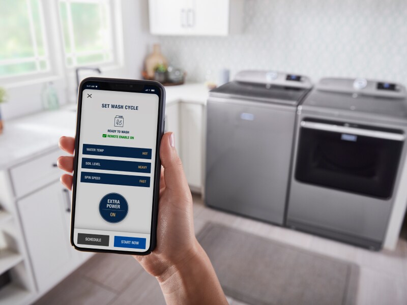 Someone using a smartphone to control a Maytag® washer and dryer Someone using a smartphone to control a Maytag® washer and dryer