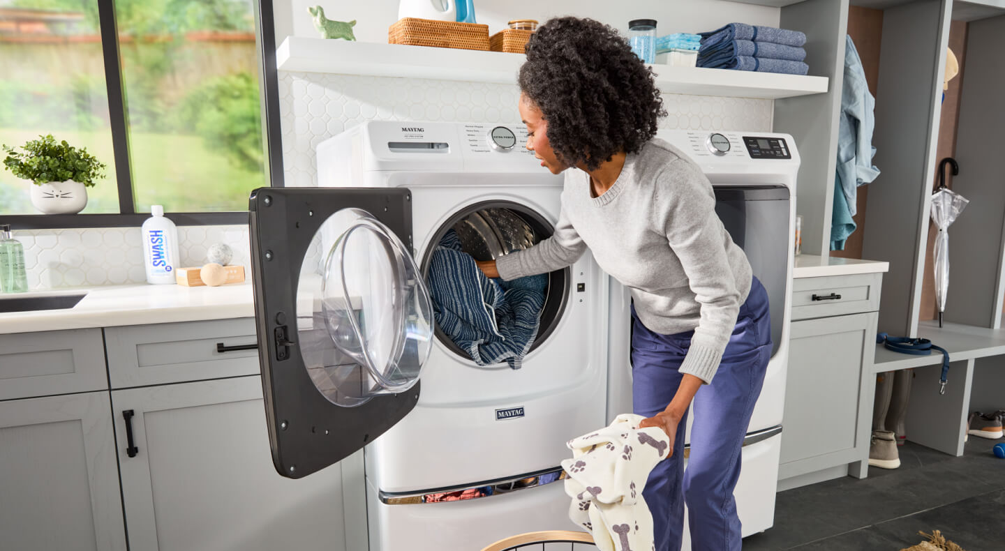 Person removing clothes from a Maytag® washer
