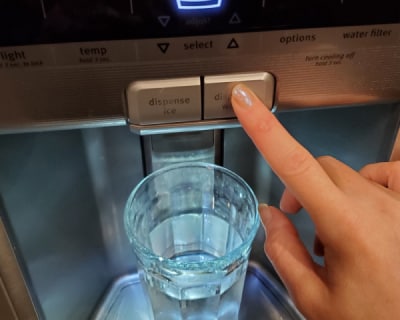 A finger pressing the water button