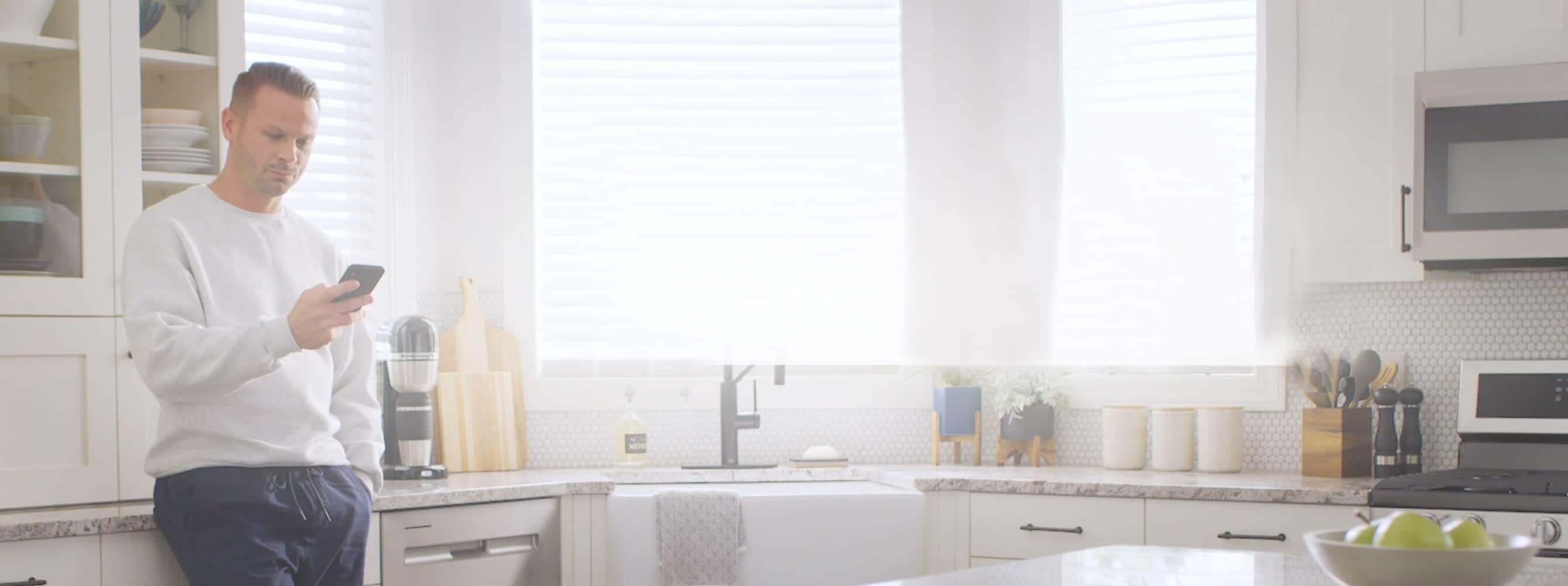 A person looking at their phone in the kitchen