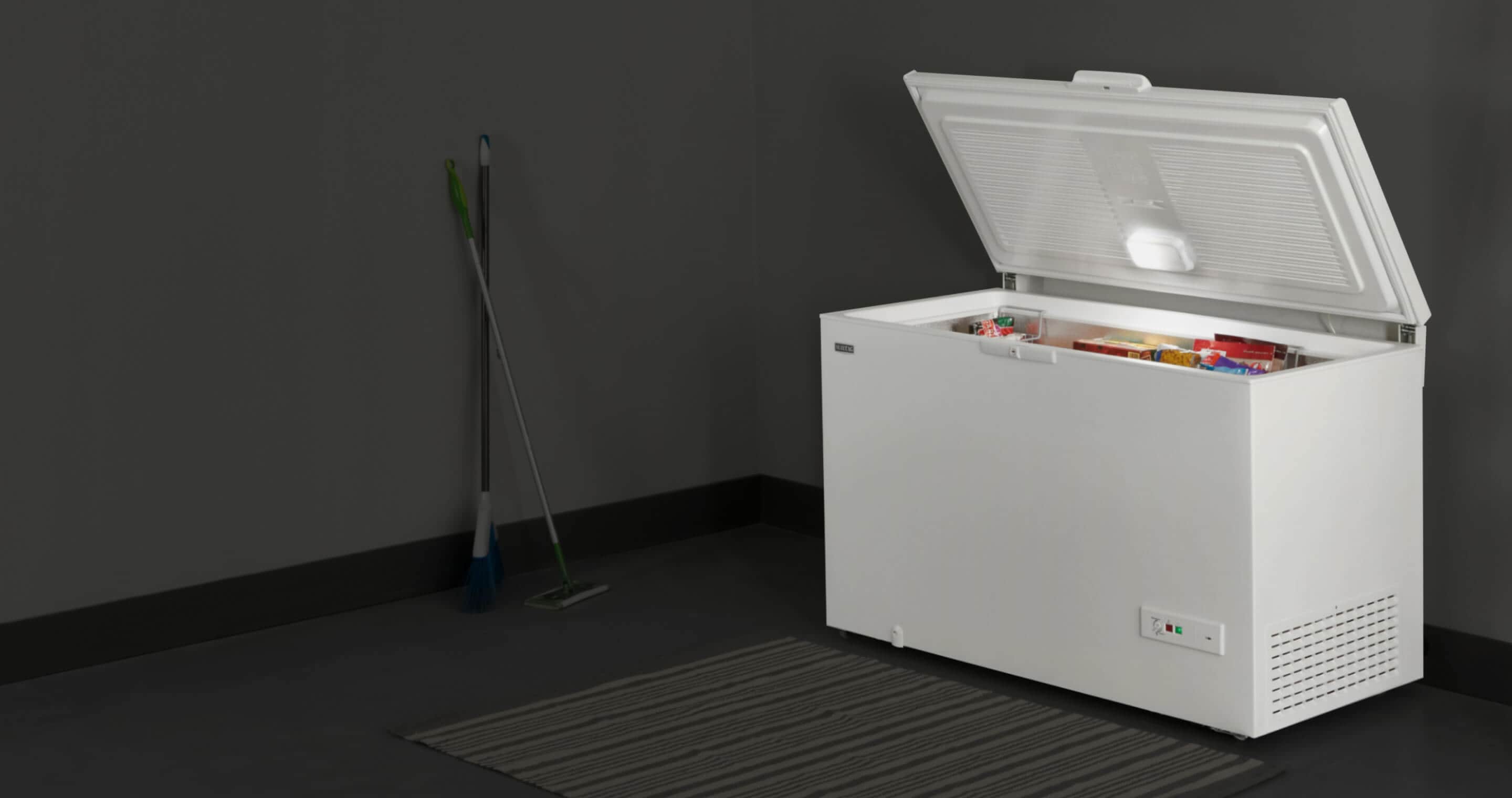 An open Maytag® chest freezer in a garage.