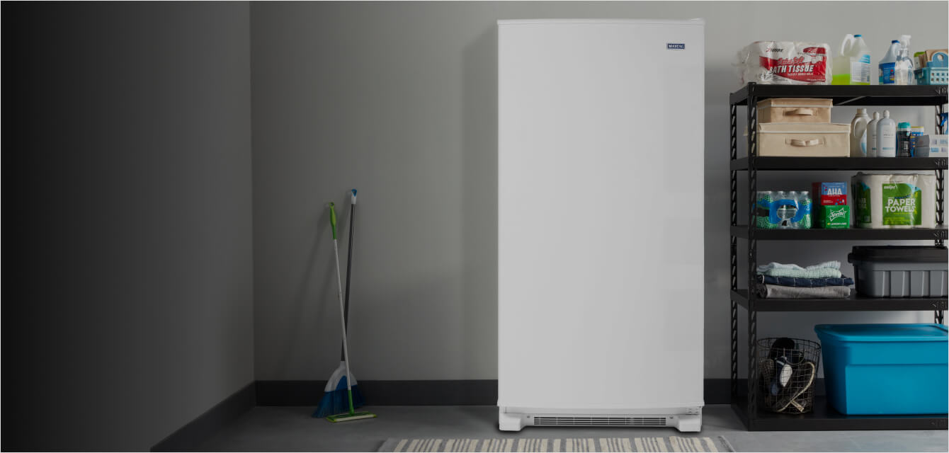 A Maytag® upright freezer in a garage.