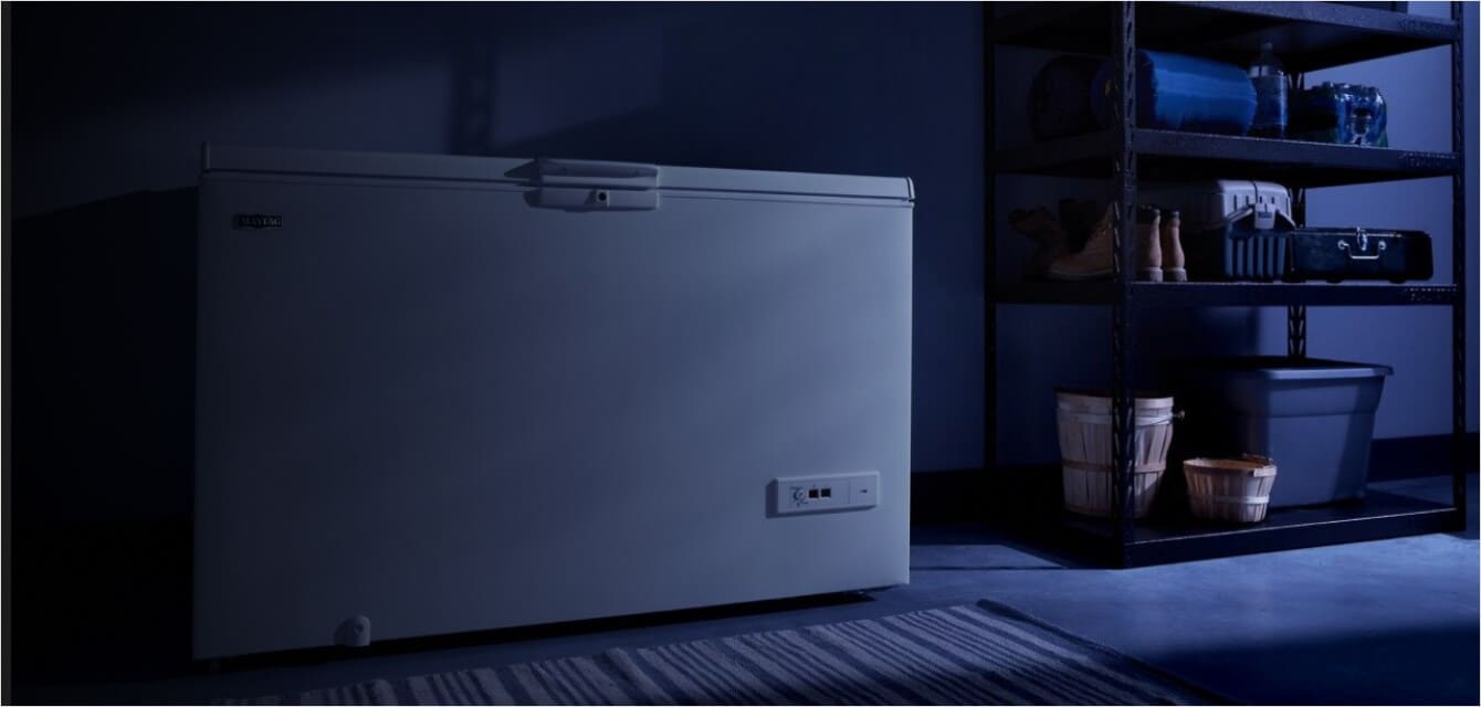 A Maytag® chest freezer in a darkened garage.