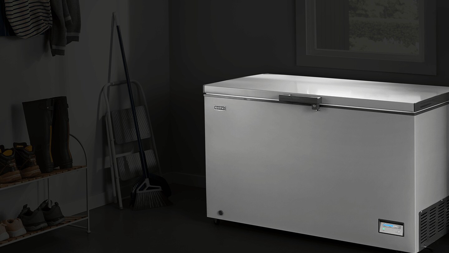 An open Maytag® chest freezer in a garage.