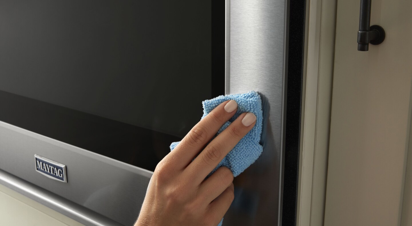 Person wiping stainless steel Maytag® appliance Person wiping stainless steel Maytag® appliance