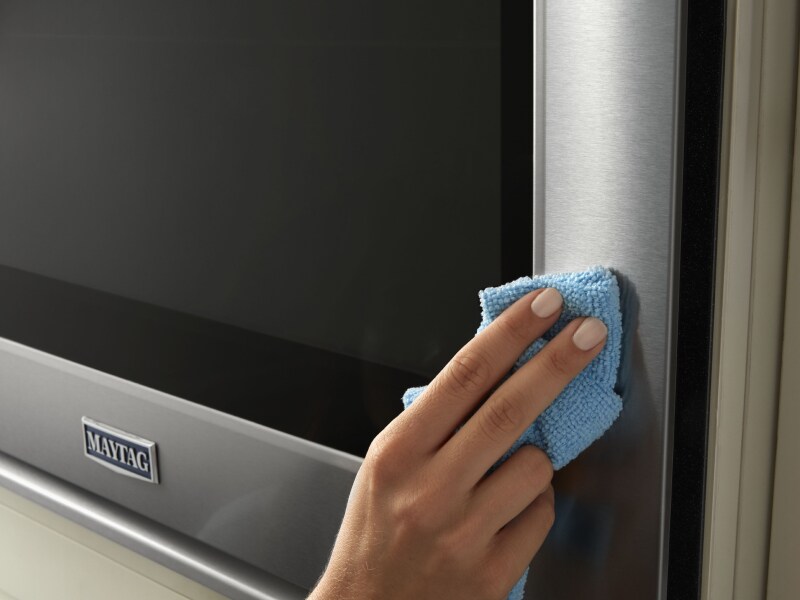 Person wiping stainless steel Maytag® appliance Person wiping stainless steel Maytag® appliance