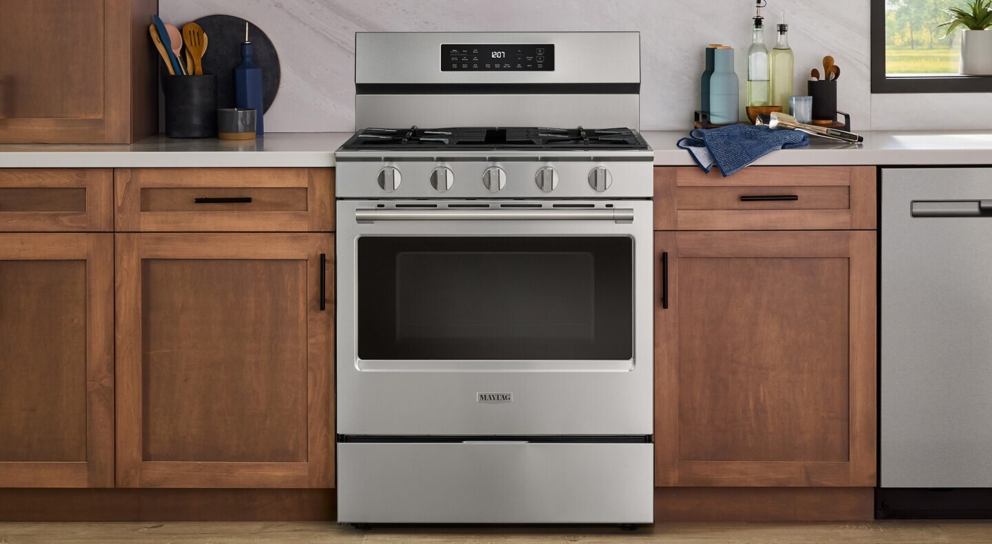 A Maytag® gas range in a kitchen with wood cabinetry