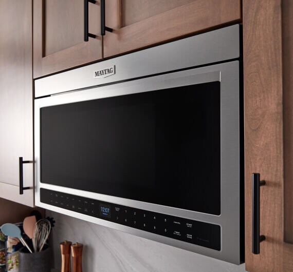 A Maytag® microwave in between kitchen cabinets.