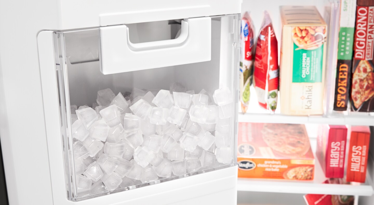 Full in-door ice bin next to frozen food items in freezer