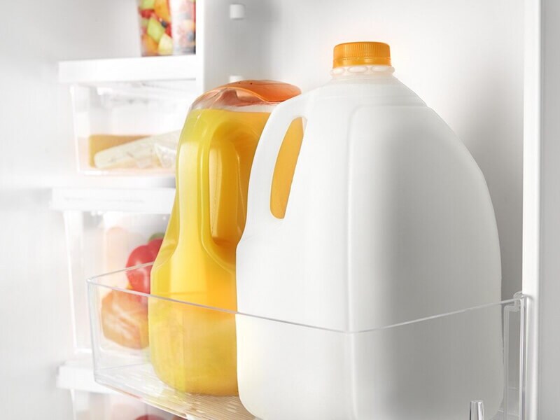 Milk and orange juice bottles in a refrigerator door shelf