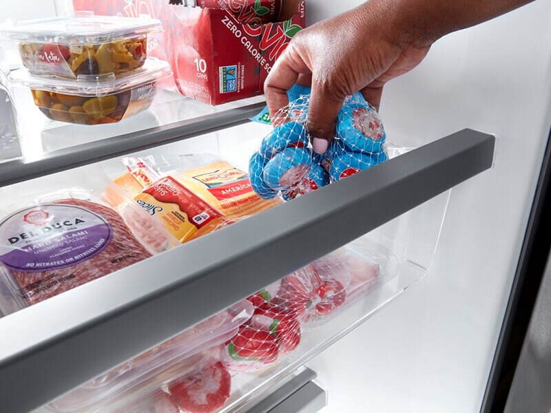Person placing snacking cheese inside a refrigerator drawer