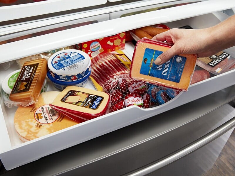 Person placing cheese inside a refrigerator drawer