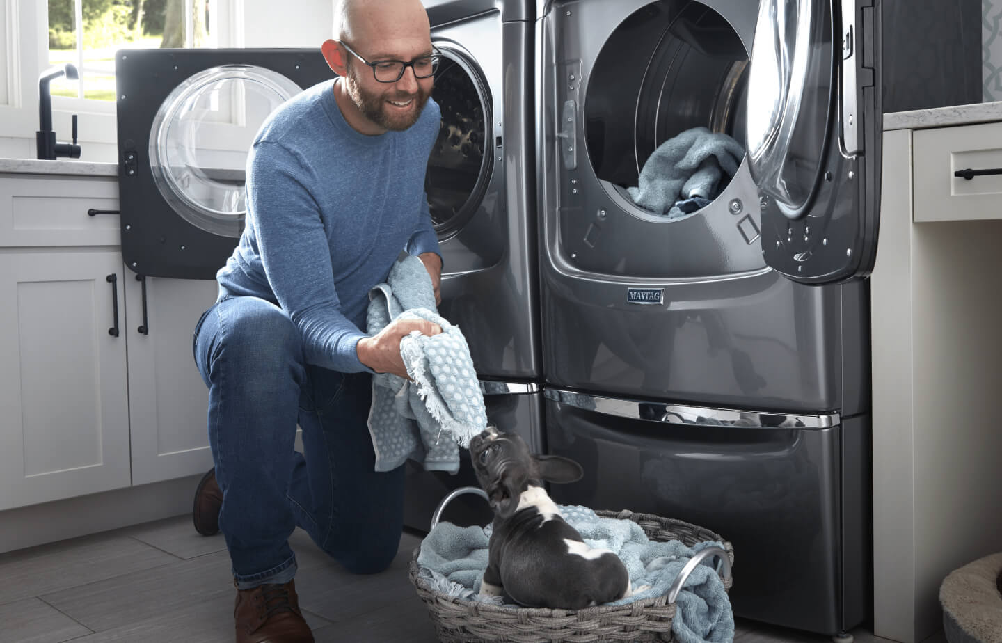 Person doing laundry with a puppy in a basket Person doing laundry with a puppy in a basket