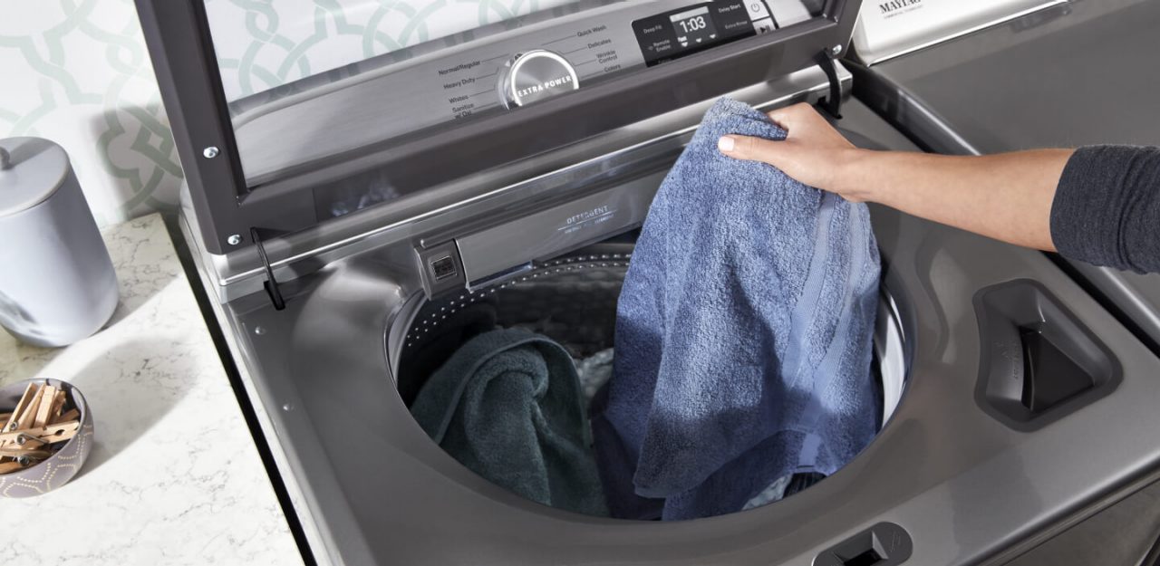 Person placing a towel in the washing machine Person placing a towel in the washing machine