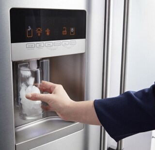 Person filling a glass of water from a refrigerator