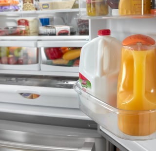 Milk and orange juice containers in a refrigerator door