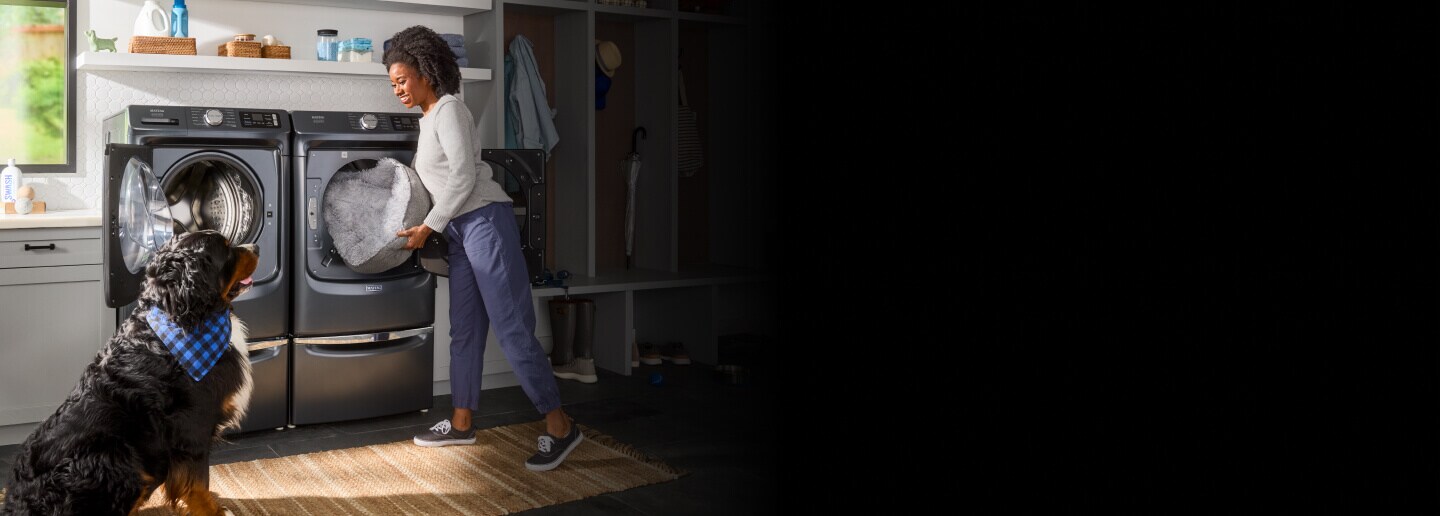 Person and a dog in front Maytag® front load washer and dryer