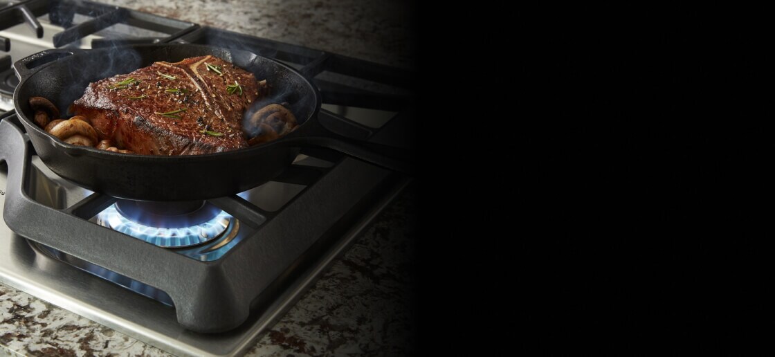 Steak searing in a cast iron skillet on a gas cooktop