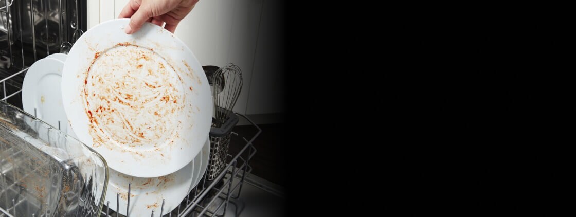 Person loading dirty dishes inside a dishwasher