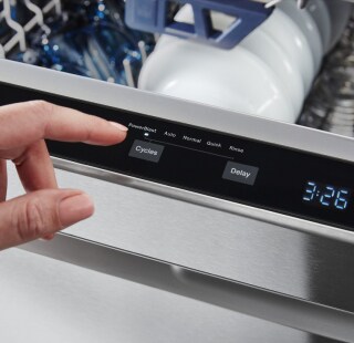 Person selecting a setting on a top control dishwasher control panel