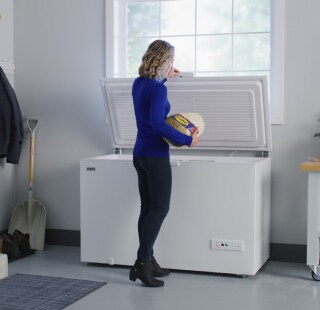 A person placing a turkey in a Maytag® chest freezer