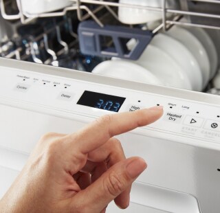 A person pressing buttons on a top panel dishwasher
