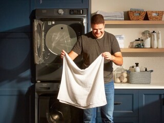 A person holding a towel in front of Maytag® laundry pair