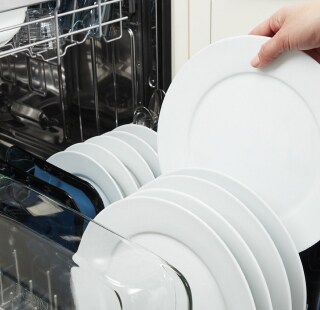 Person removing clean dishes from a dishwasher