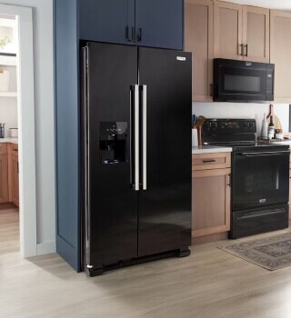 A black refrigerator with a black over-the-range microwave and range