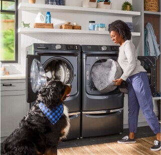 A person and dog in front of washer and dryer