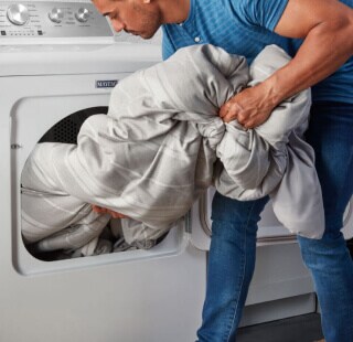 A person removing a comforter from a dryer