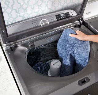 A person placing clothes into a washing machine