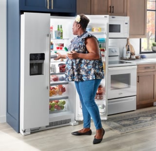 A person looking inside their open refrigerator.