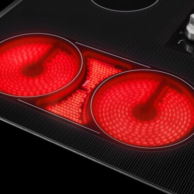 A close-up of a Maytag® electric cooktop with the burners on