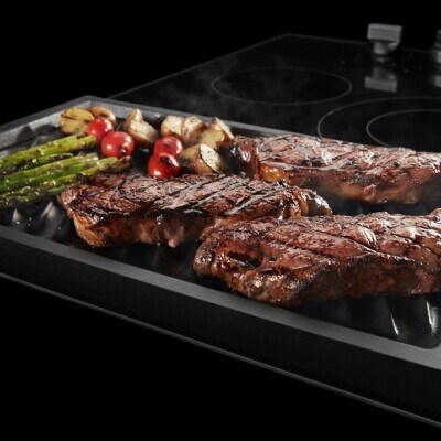 A close-up of food cooking on a Maytag® reversible grill