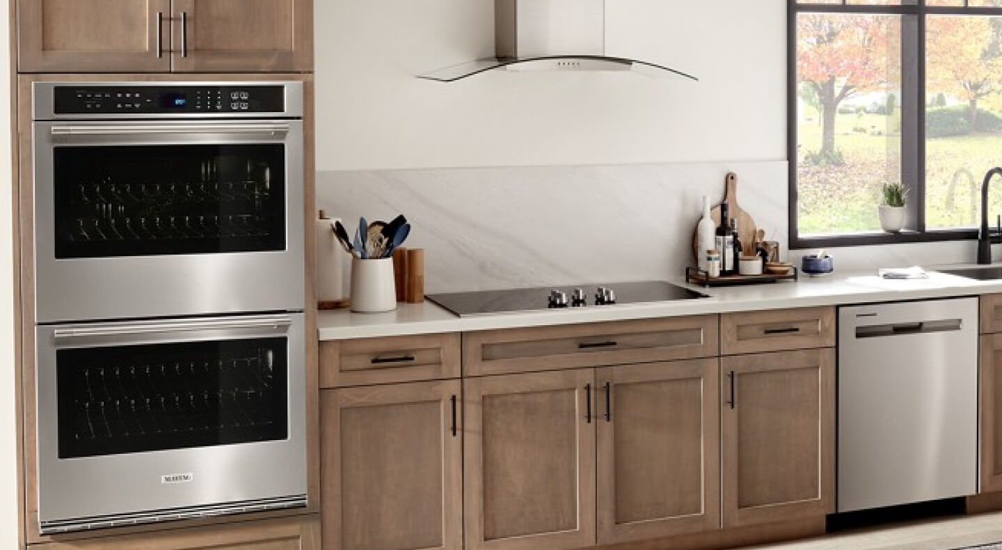 A Maytag® electric cooktop, range hood and double wall oven in a modern kitchen