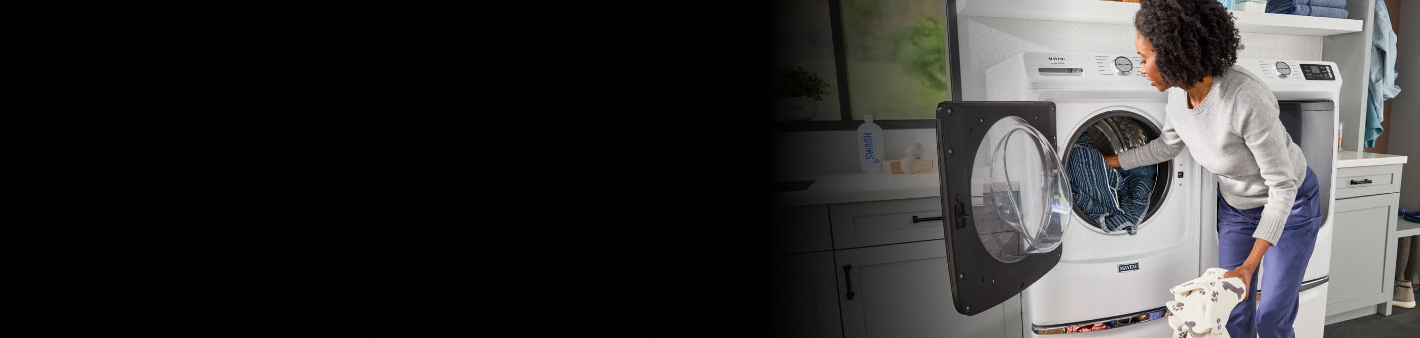 Person loading clothes into a white Maytag® front load washer