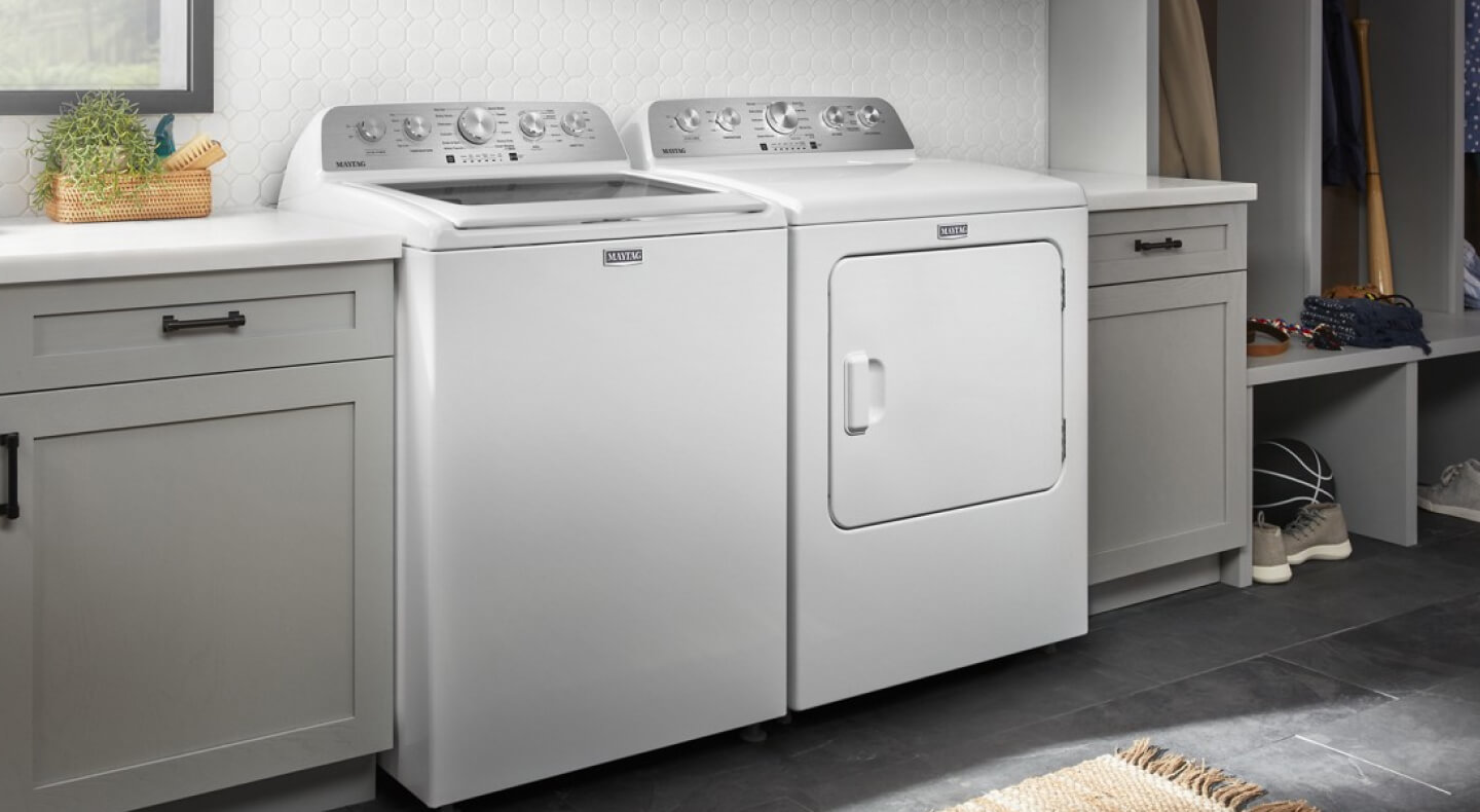 A laundry room with a white Maytag® top load washer and dryer set