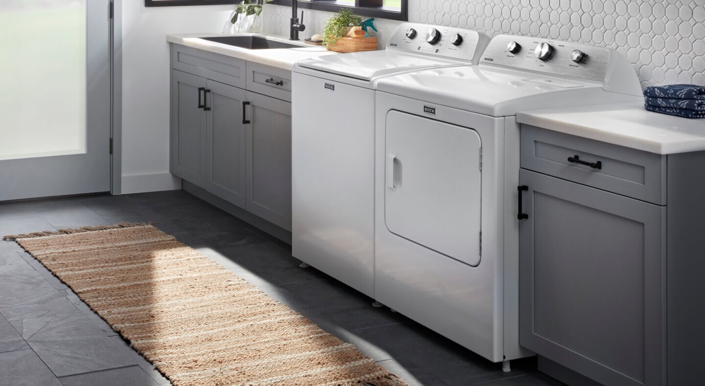 A Maytag® top-load washer and dryer set in a laundry area