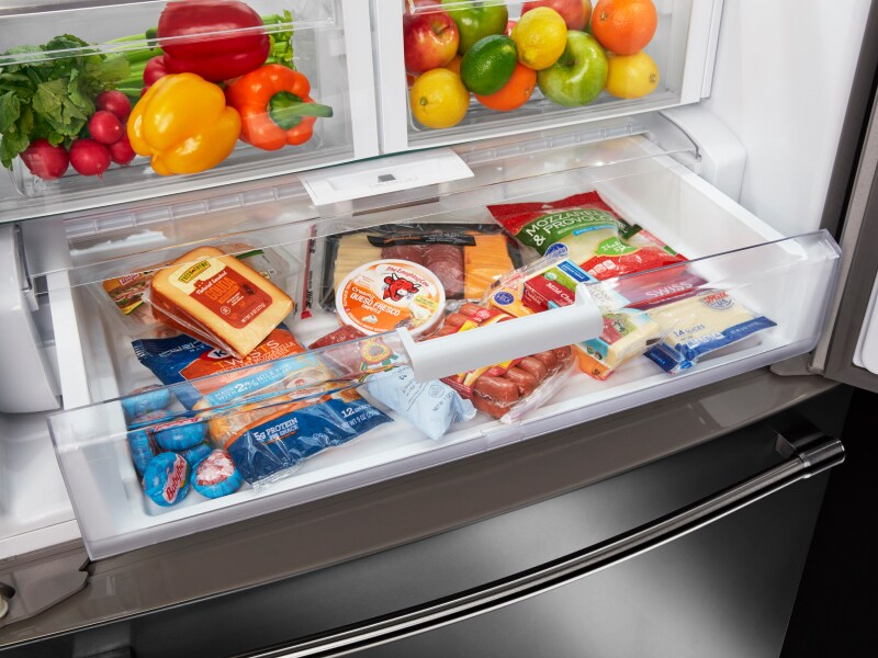 An open drawer inside a refrigerator featuring various deli meats and cheeses