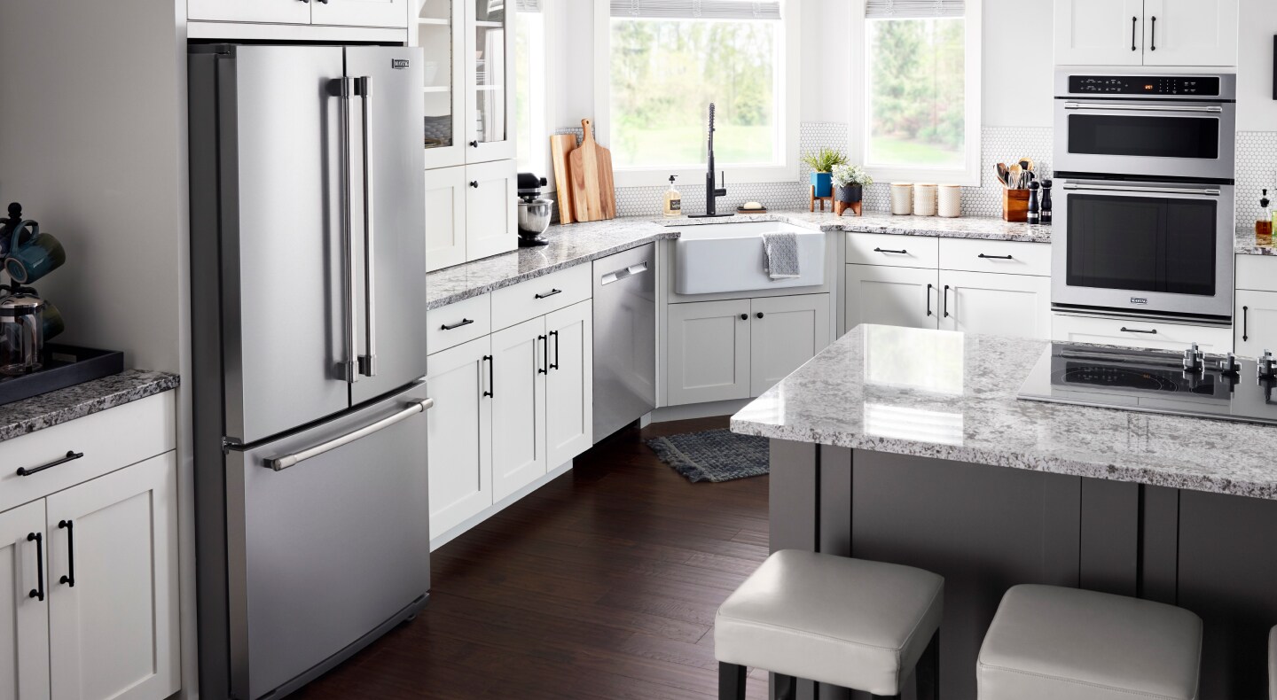 White kitchen with black hardware featuring Maytag brand refrigerator and wall oven