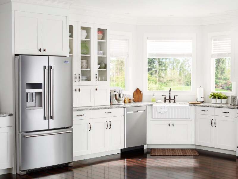 White kitchen with stainless steel French door refrigerator and dishwasher
