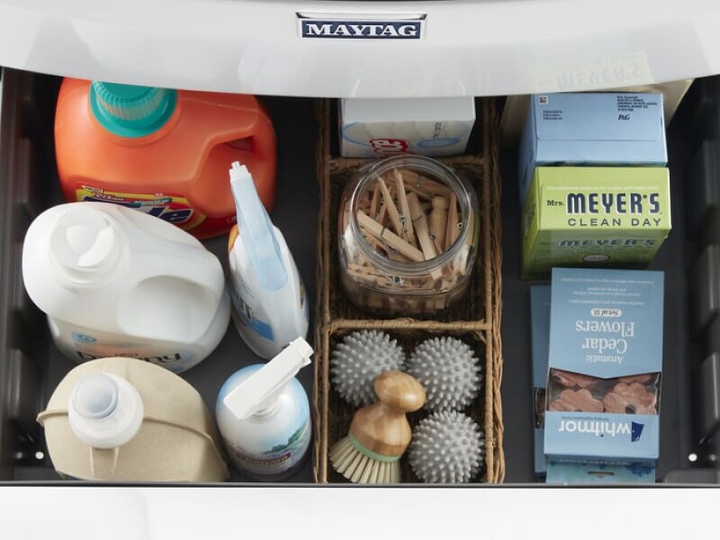 Laundry cleaning supplies in a storage drawer under a washing machine
