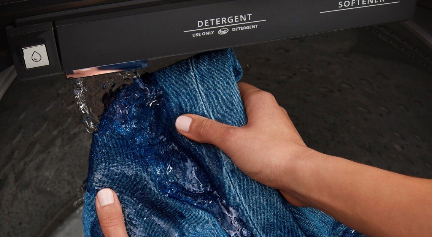 Hands pre-treating denim with built-in water faucet Hands pre-treating denim with built-in water faucet