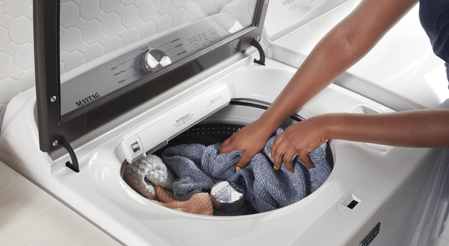 A person pulling a towel out of a washer
