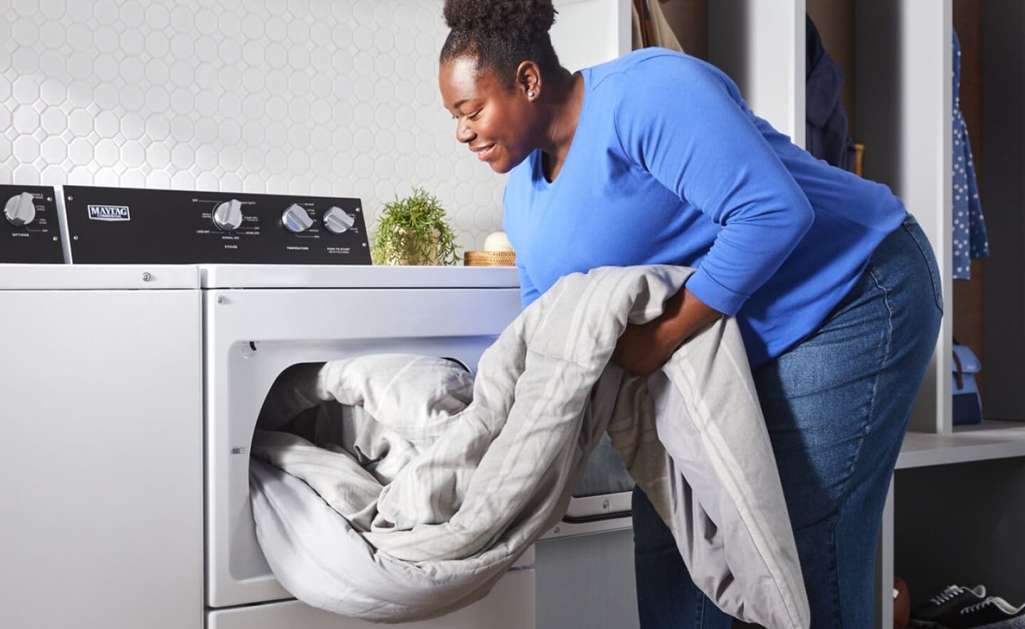 A person pulling clothes out of a washer A person pulling clothes out of a washer